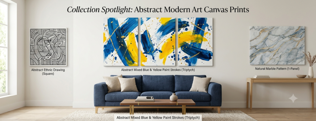 A wide 1920x739 banner displaying three modern abstract art canvas prints arranged on a clean gallery wall above a blue sofa and wooden console table. The central artwork is a bold blue and yellow paint stroke triptych, flanked by a square black-and-white graphic linework piece on the left and a soft gray and gold natural marble canvas on the right.