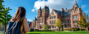 University campus in the United Kingdom with an international student walking toward a historic academic building.